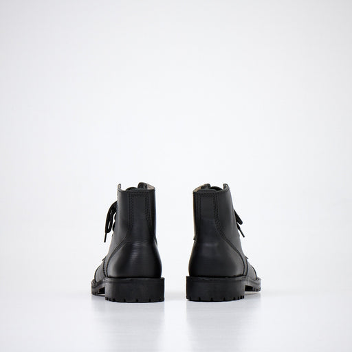 1. Back view of AIPI A-PS-2 black leather boots with lace-up closure, showcasing durable rubber sole in studio setting