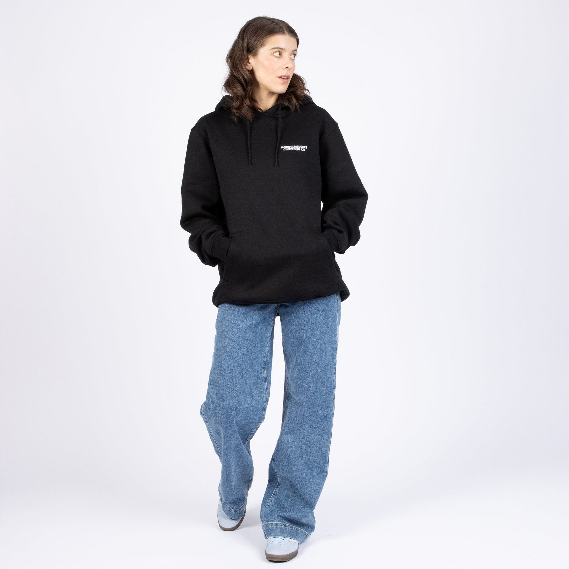 1. Woman wearing black Pippi Longstocking unisex heavy hoodie by Moomin, styled with blue jeans in studio setting