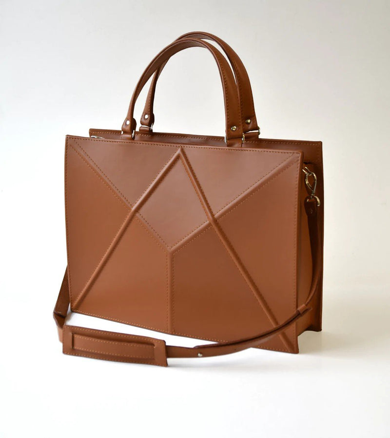 1. Woman holding Zelma Kraft black small briefcase handbag with adjustable strap, styled with pink blouse and jeans
