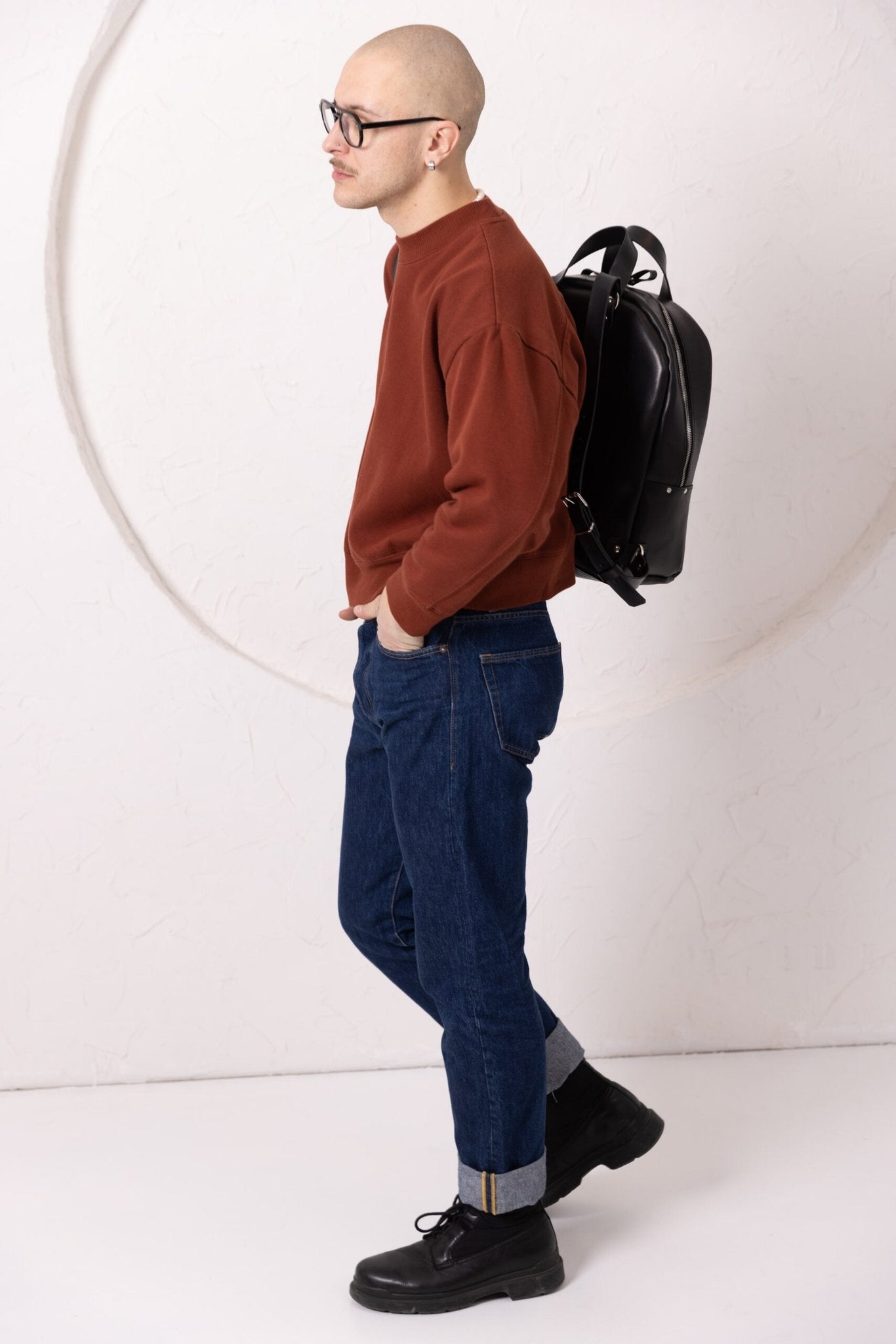 8. Woman holding TOKS VISOKS GORDON black leather backpack, highlighting spacious interior in lifestyle setting