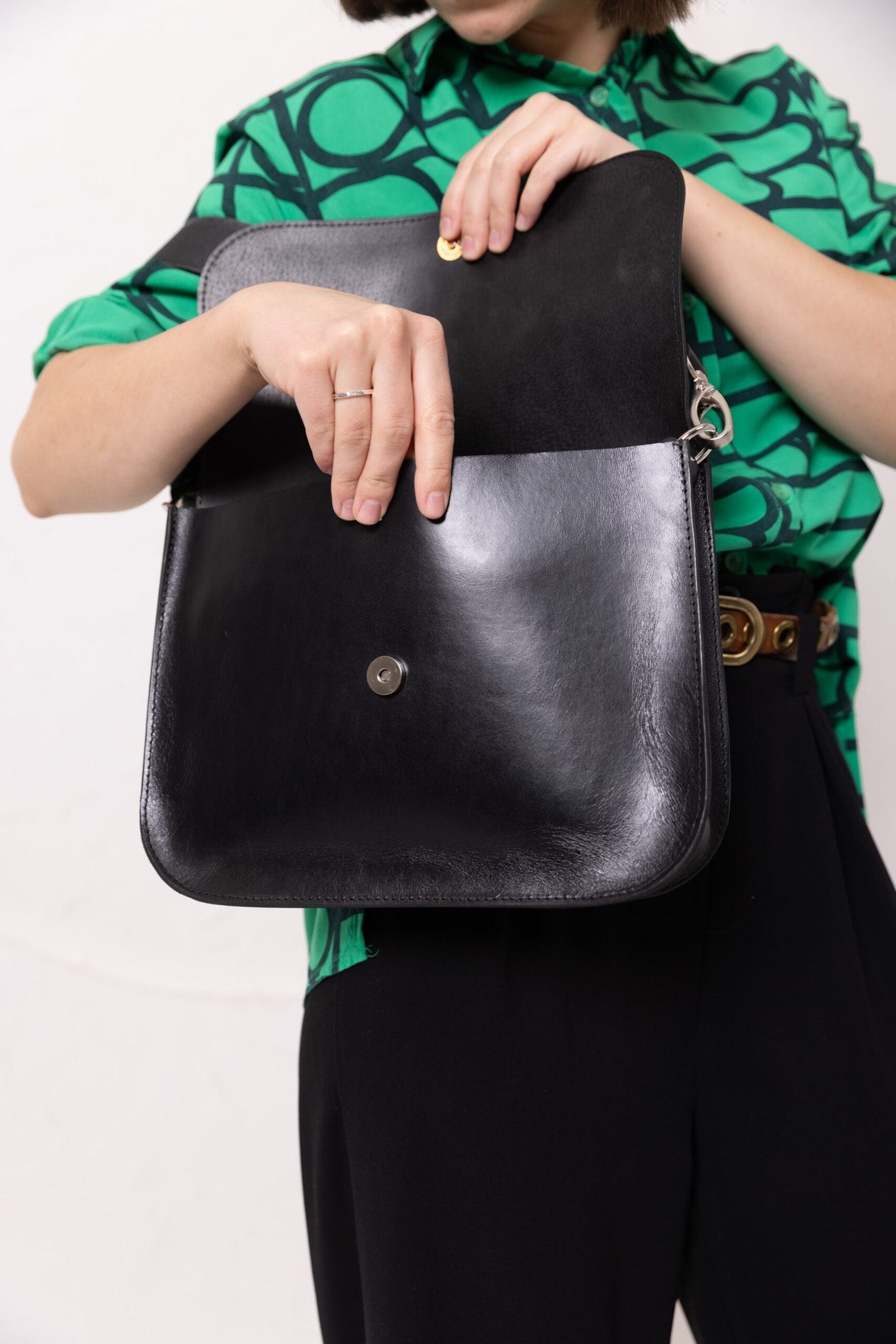 10. Close-up of TOKS VISOKS ASTORIA black suede handbag with snap buckle closure, held by woman