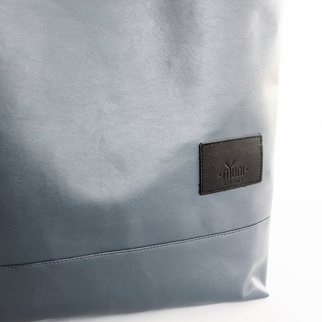 5. Close-up of Muni logo on grey faux leather backpack