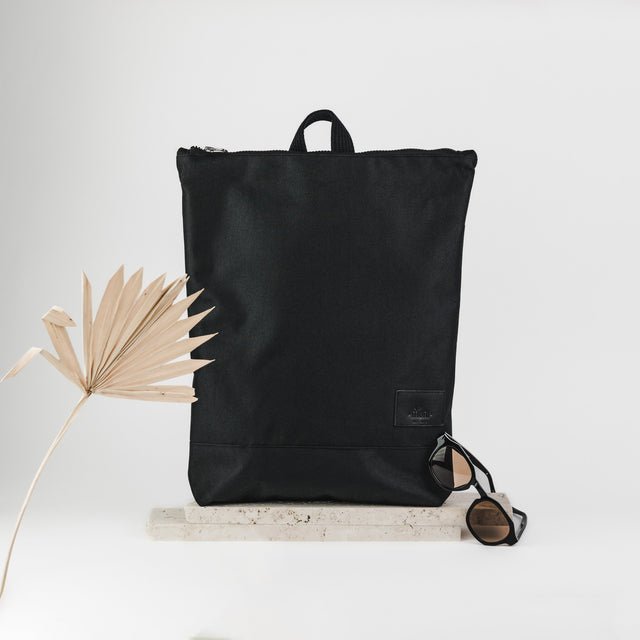 8. Lifestyle shot of Muni black leather backpack with sunglasses, showcasing chic urban style