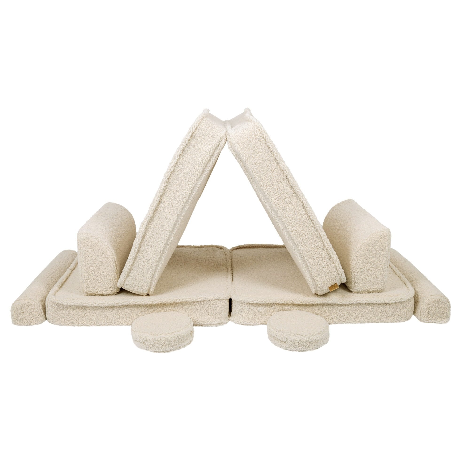 8. Cream sofa cushions arranged in a tent-like structure with circular cushions, showcasing creativity in a studio setting