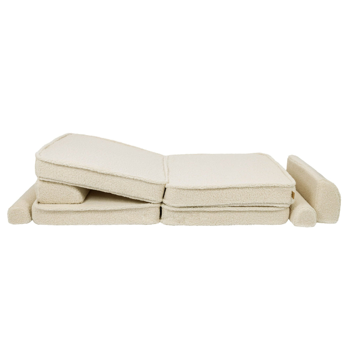 7. Cream sofa cushions folded in a zigzag pattern with armrests, highlighting modular design in a studio setting