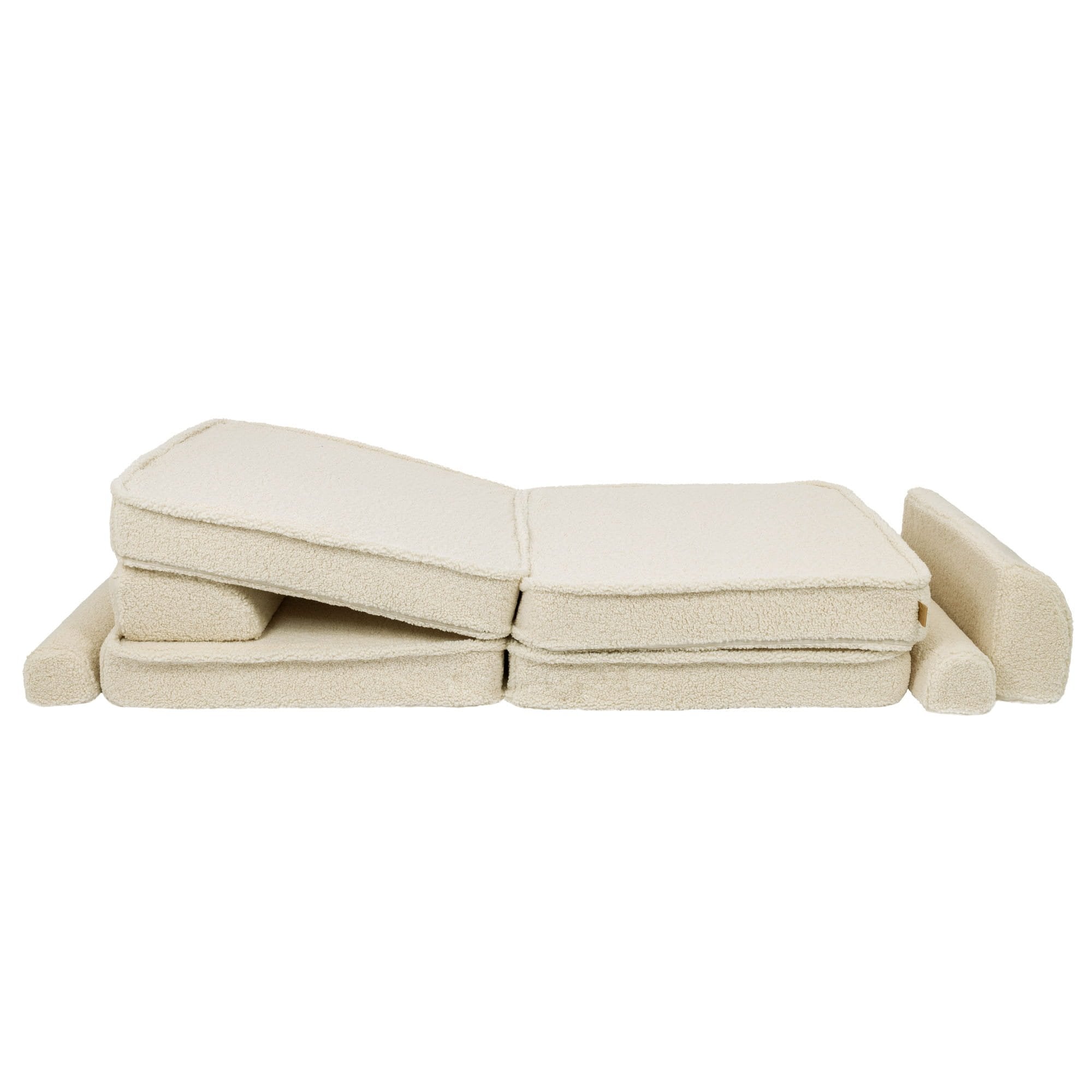 7. Cream sofa cushions folded in a zigzag pattern with armrests, highlighting modular design in a studio setting
