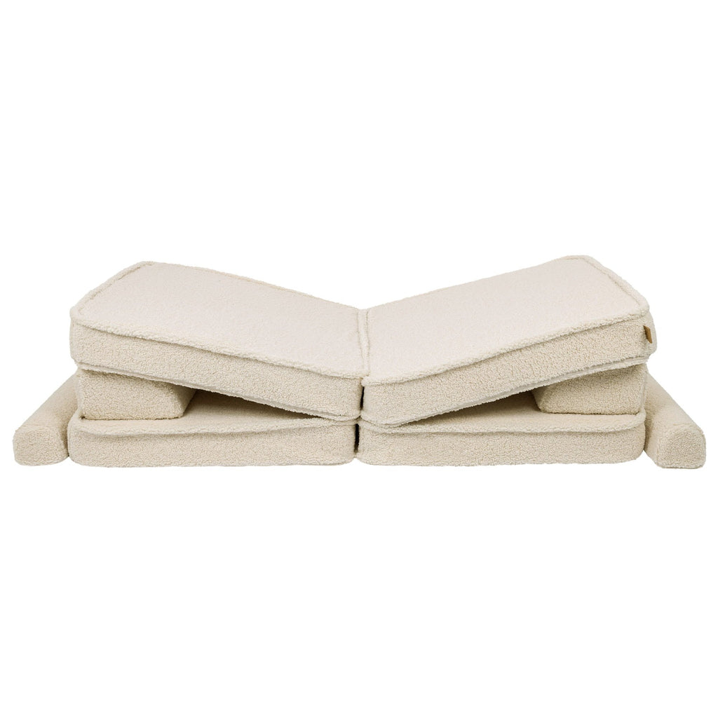 5. Cream sofa cushions folded in a zigzag pattern, showcasing modular flexibility in a studio setting