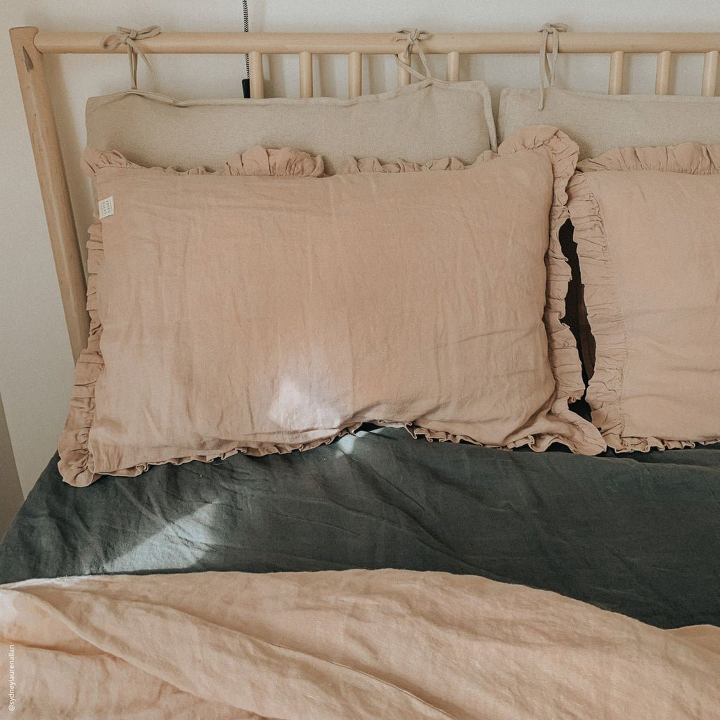 12. Beige frilled linen pillowcases on a bed with a wooden headboard, warm and inviting bedroom