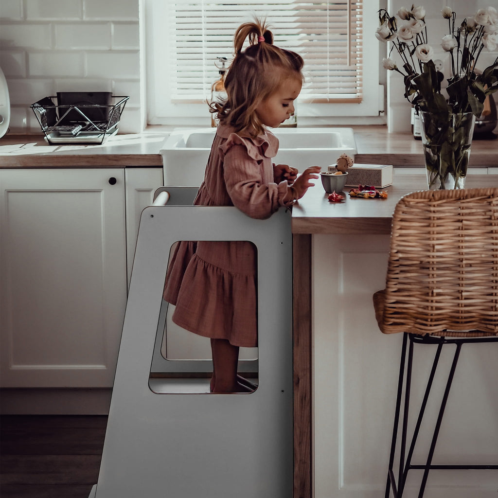 1. Child standing on MeowBaby gray kitchen helper reaching kitchen counter in bright kitchen