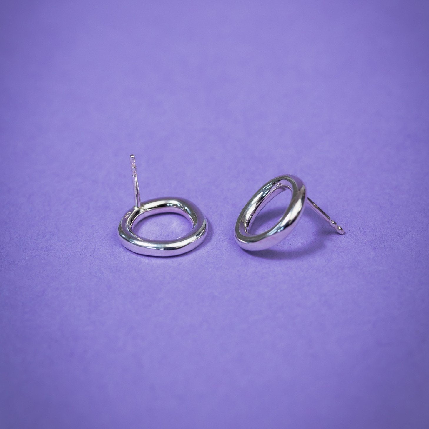 3. Close-up of Maarja Palu Earrings IRREGULAR x1 in polished silver on purple background, highlighting geometric design