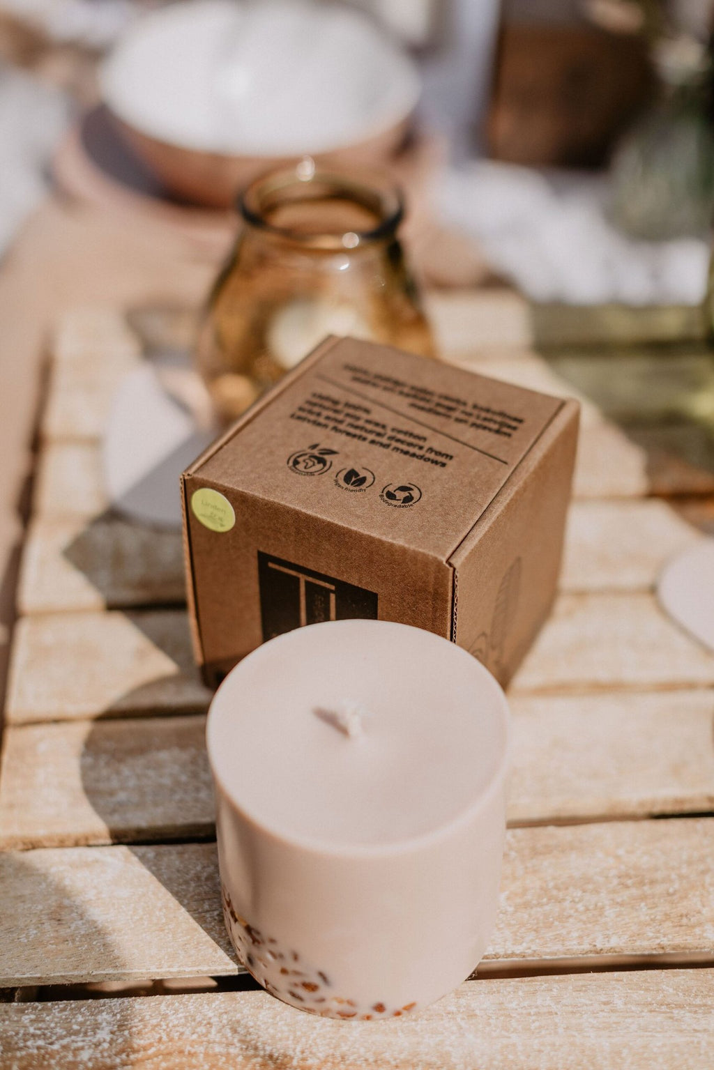 3. TL Candles hand-made soy wax candle with amber pieces and packaging, styled with green glass decor