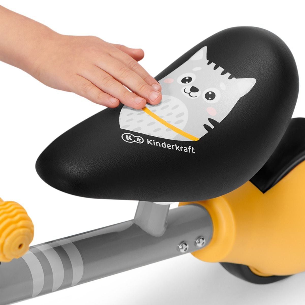 3. Close-up of Kinderkraft CUTIE balance bike seat with kitten print and child's hand