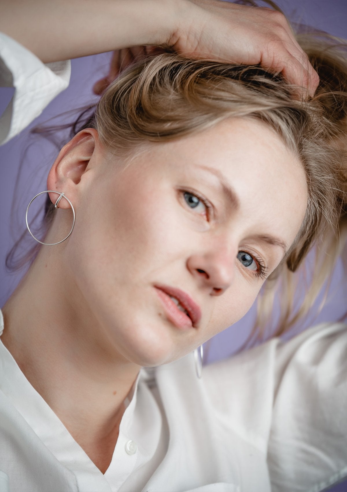 2. Woman styling hair while wearing Maarja Palu LAYERS x1 large silver earrings