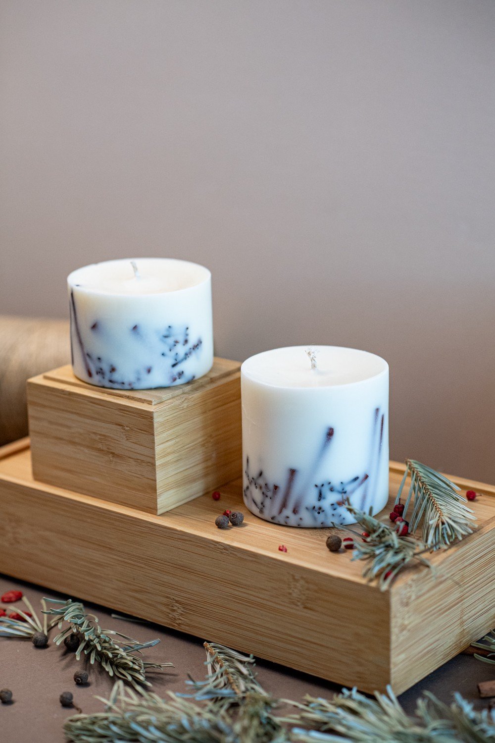 6. Two white soy wax candles with lavender decoration on wooden display, surrounded by herbs