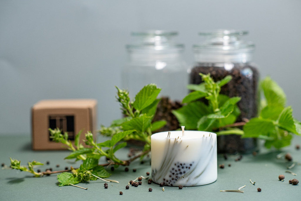 2. TL Candles hand-made soy wax candle with juniper fragrance, shown with natural elements and packaging