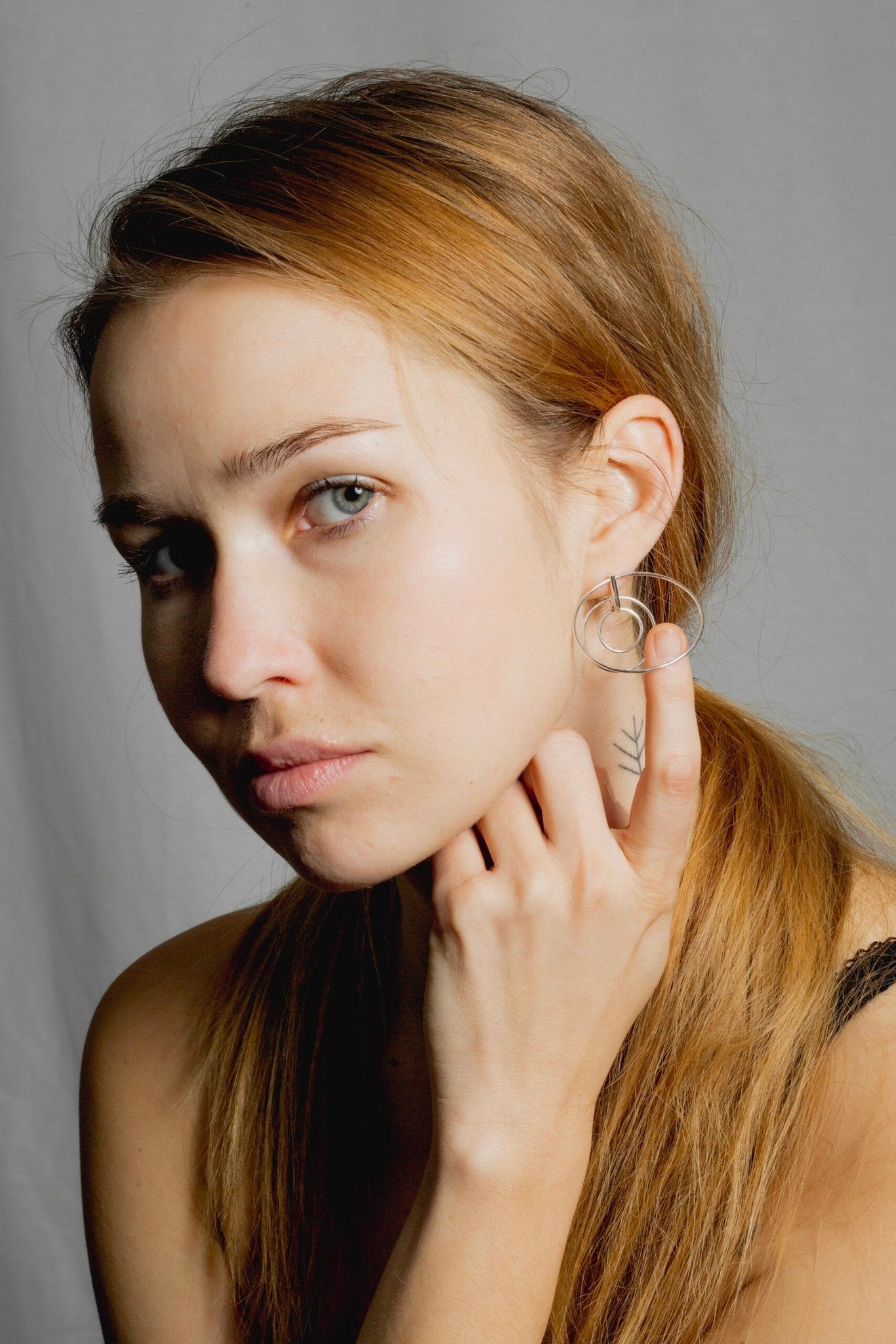 1. Woman wearing Maarja Palu LAYERS x3 silver earrings with interlocking circles, shown in lifestyle setting