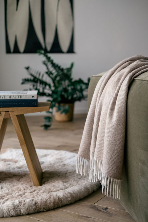 1. Natural Alpaca Wool Throw in beige draped over a sofa in a cozy living room setting