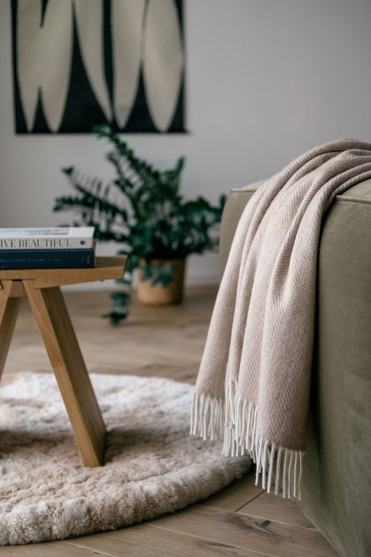 1. Natural Alpaca Wool Throw in beige draped over a sofa in a cozy living room setting