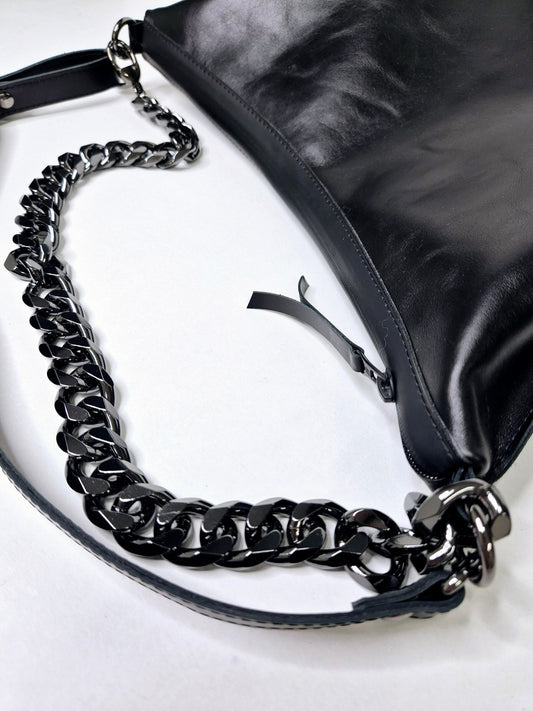 2. Woman holding Zelma Kraft black leather hobo bag with gold chain strap in outdoor setting