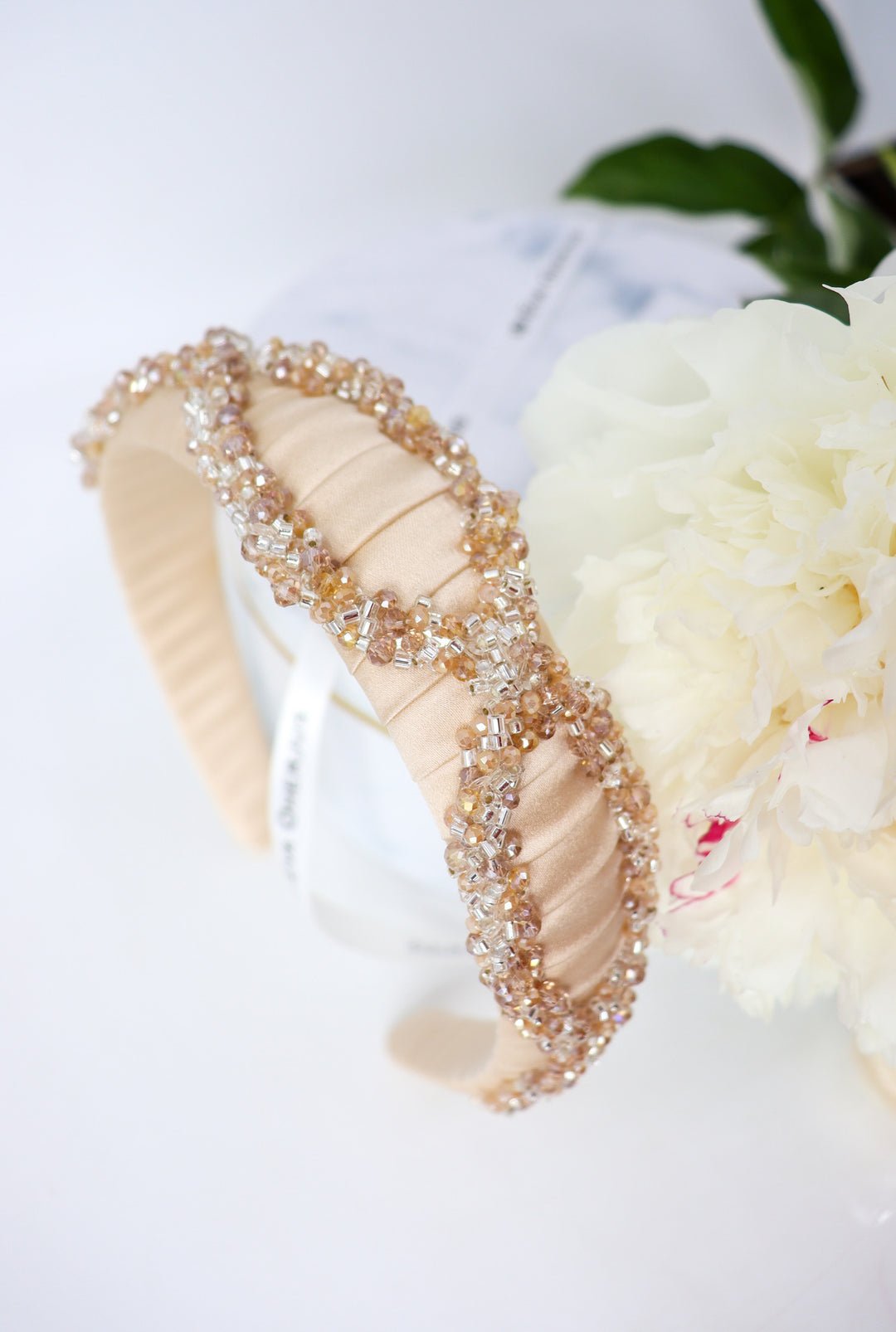 4. Close-up of Eva Oherjus Mulberry Silk Headband Ada with beige and crystal clear beading on hat box