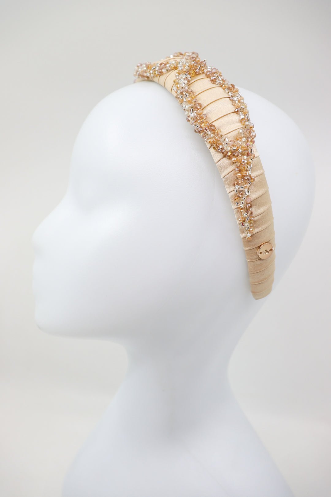 3. Side view of Eva Oherjus Mulberry Silk Headband Ada Thin on mannequin, highlighting beige silk and crystal details