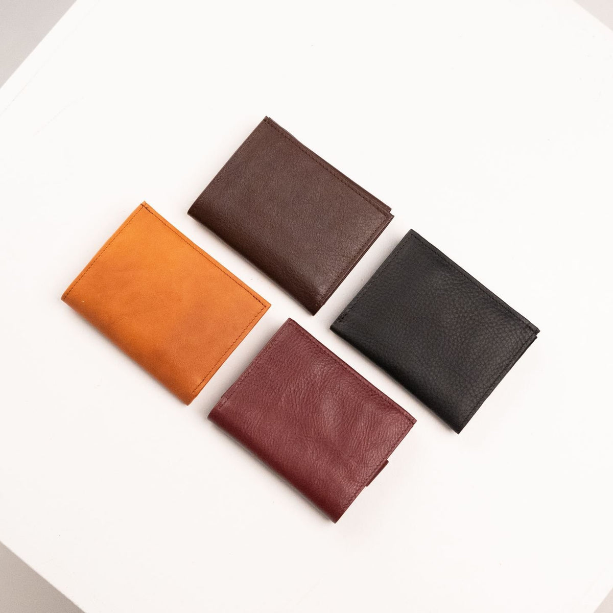 1. Men's leather wallets by Papillon in Bordeaux, Cognac, Dark Brown, and Black, shown in flat lay