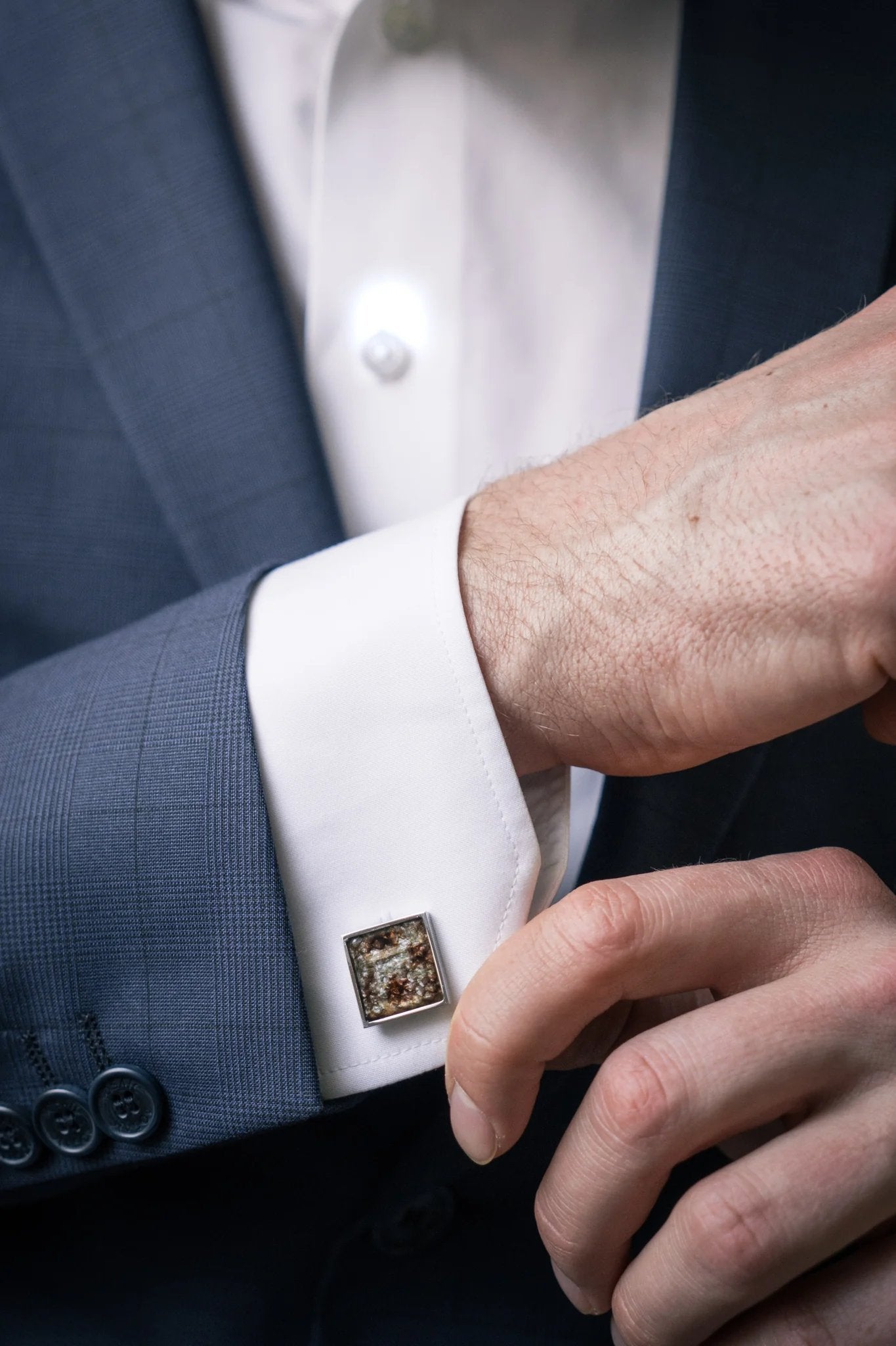 1. Man wearing a suit with Eherüs square cufflinks made from black-spotted brown trout leather on white shirt cuff