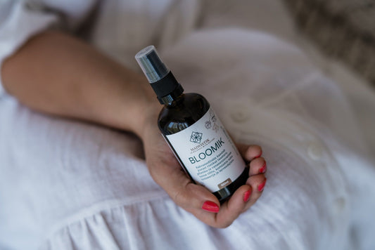 2. MaiWistik BLOOMIK 2in1 Body and Massage Oil 100ml held by a woman in a relaxed indoor setting