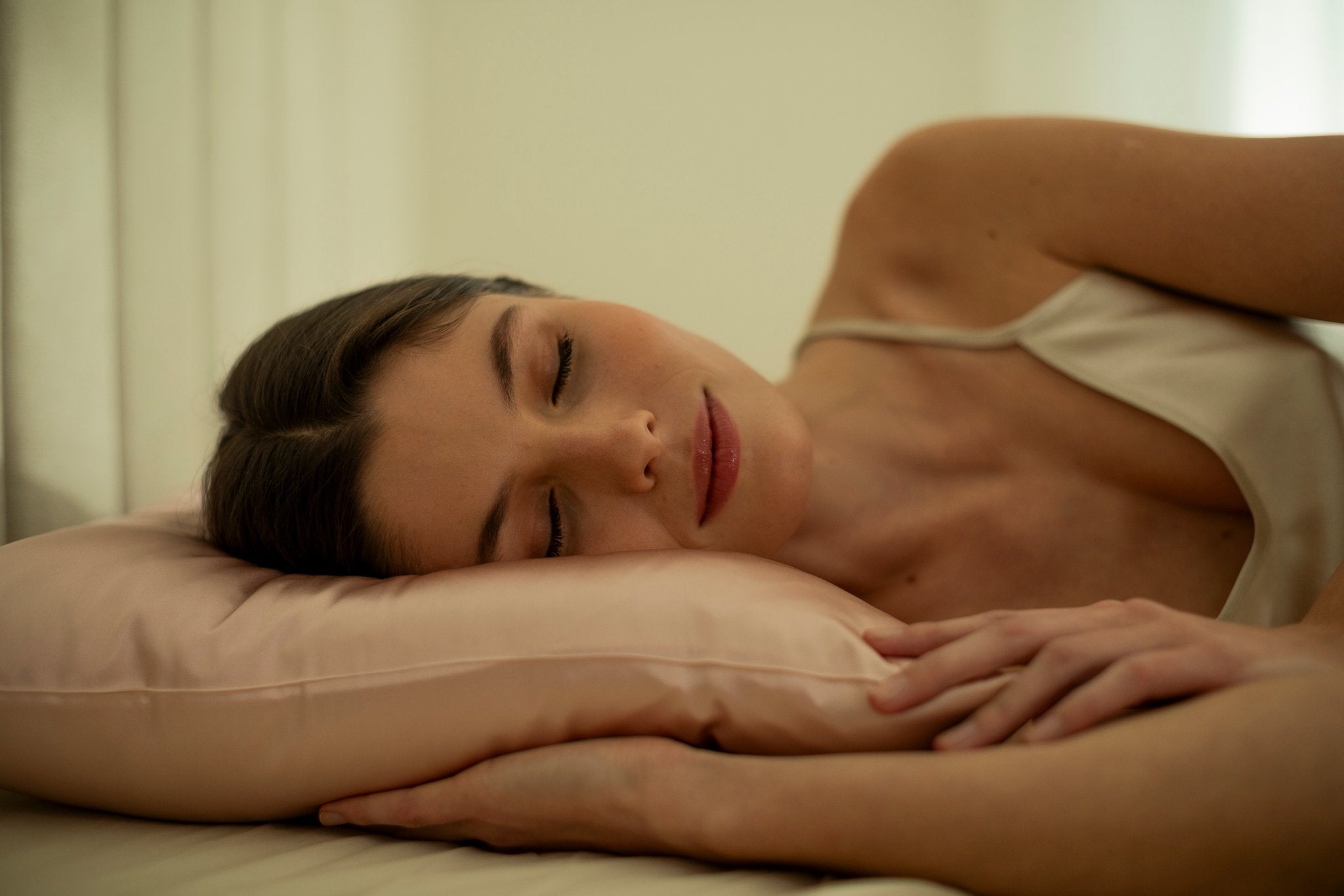 15. Woman resting on pink Mulberry silk pillowcase in a softly lit room, highlighting comfort
