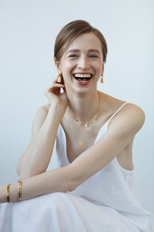 2. Smiling woman wearing Stargazer Choker in gold by New Vintage by Kriss, styled with matching jewelry