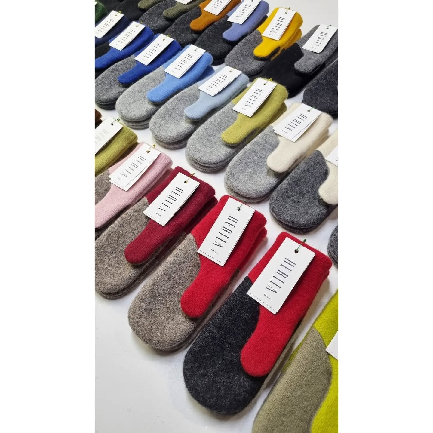 3. Assorted colors of HERTTA felted wool mittens displayed with tags, highlighting variety