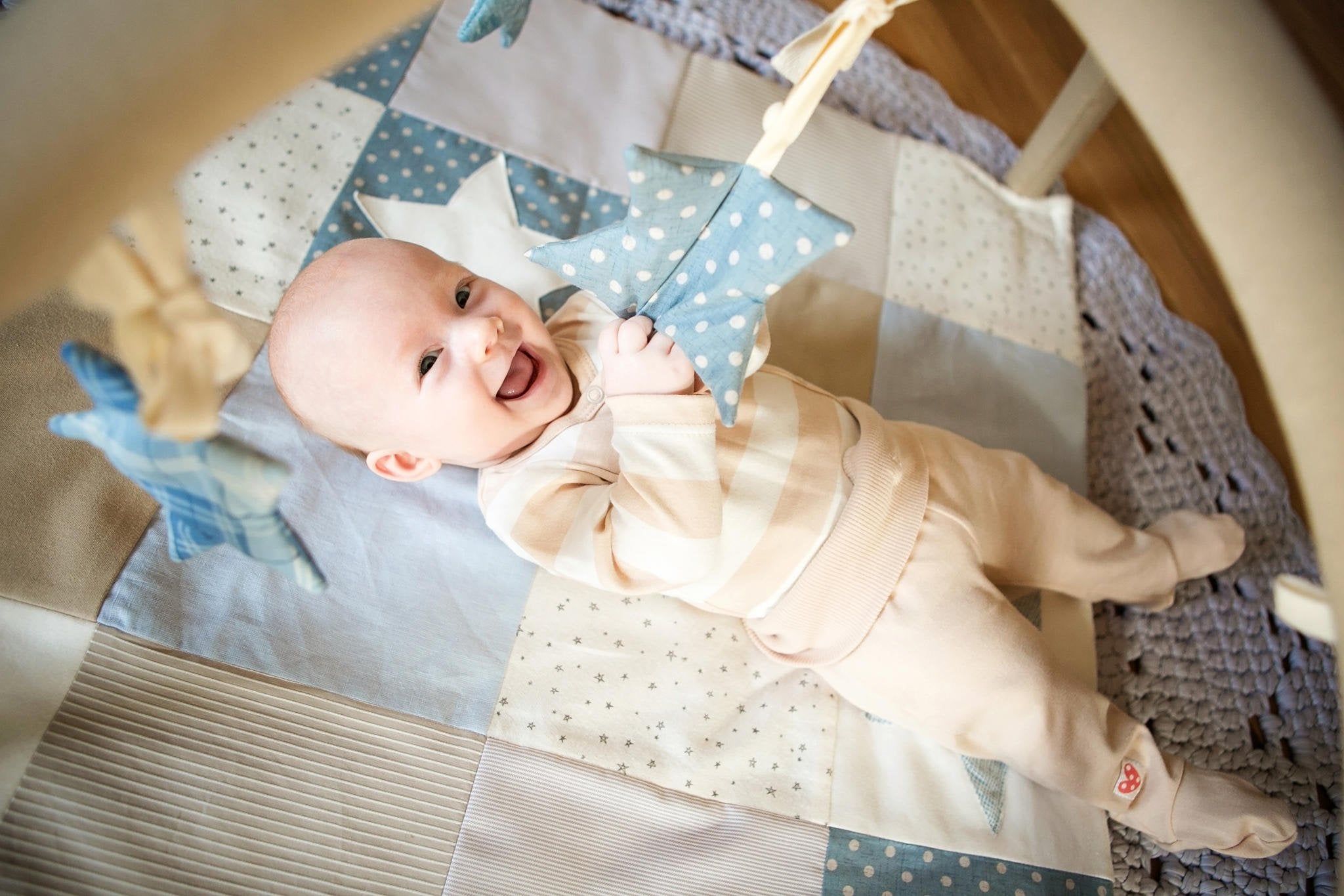 2. Smiling baby lying on Karloova activity mat with blue star toy