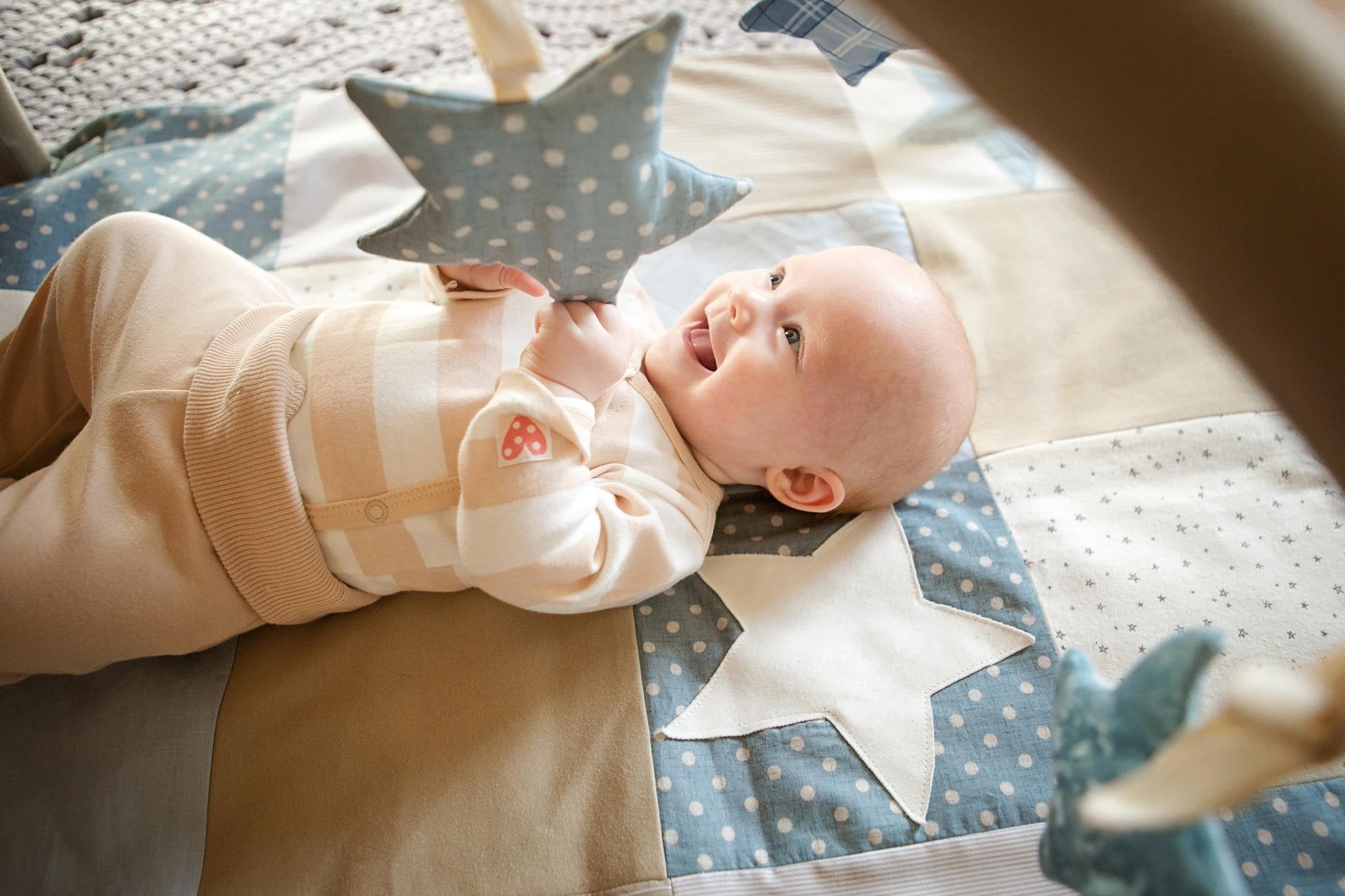 2. Baby reaching for blue polka dot star toy on Karloova activity mat