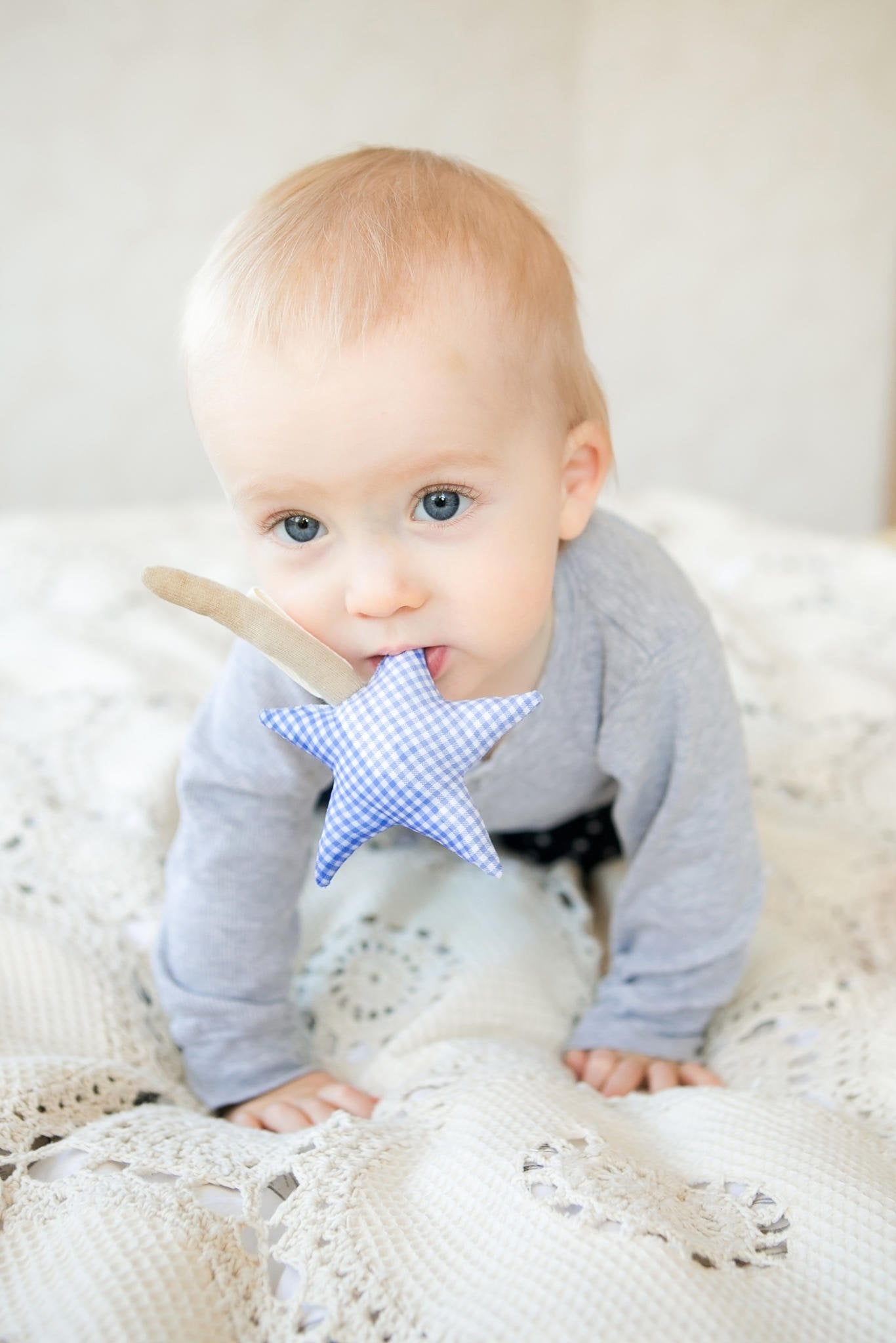 4. Baby chewing on blue star-shaped Karloova Magic Wand on crochet blanket