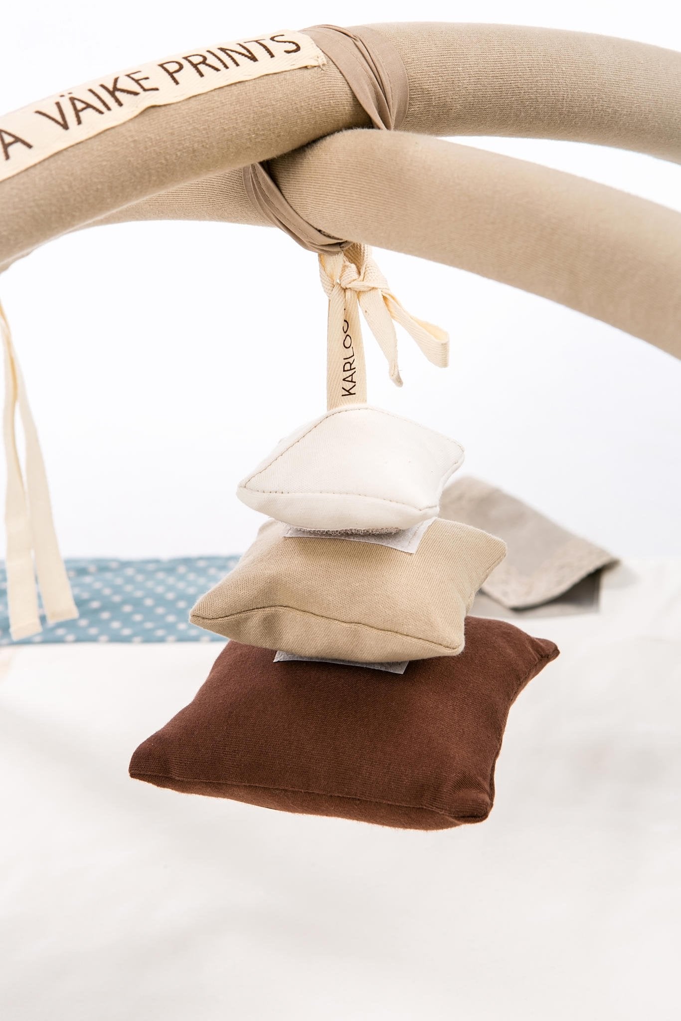 1. Karloova Pillow Heap baby toy suspended from activity arch with beige, brown, and white pillows