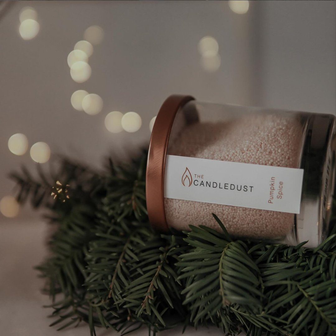 7. Candledust Pumpkin Spice powdered candle in a glass container with rose gold lid, surrounded by festive greenery
