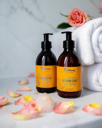 2. Lifestyle image of Nurme Zesty Orange Shower and Hand Wash Gel and Sea Buckthorn Vitamin Care Body Lotion with rose petals and towels