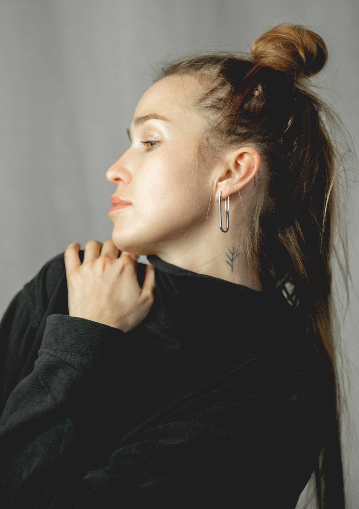 1. Woman wearing Maarja Palu TECTONICS silver earrings, showcasing modern elongated U-shaped design
