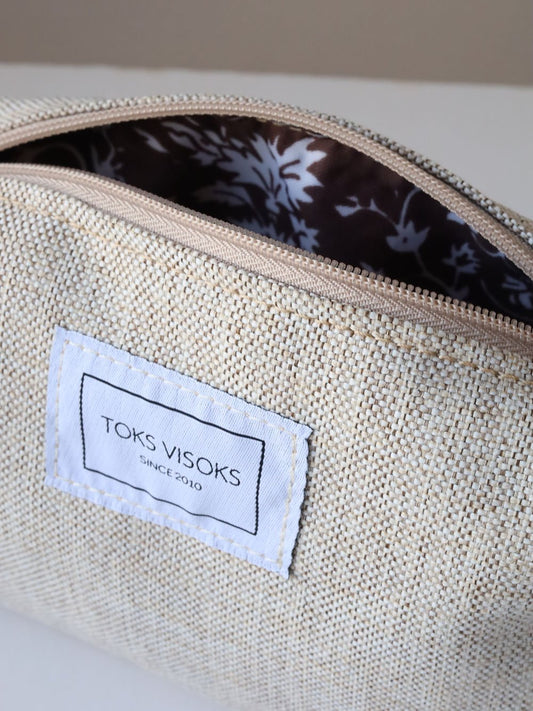 1. Close-up of TOKS VISOKS LORNA Makeup Bag in White Sand, showing interior floral lining and brand label
