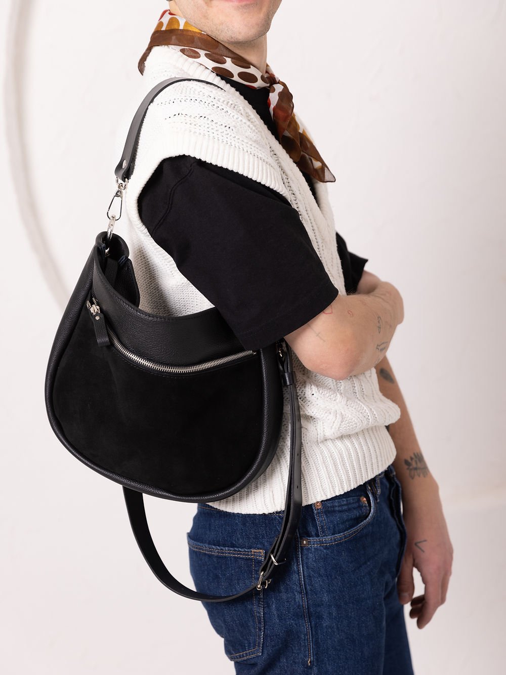 2. Unisex model wearing TOKS VISOKS STELLA black leather handbag with adjustable strap, styled with casual attire in studio
