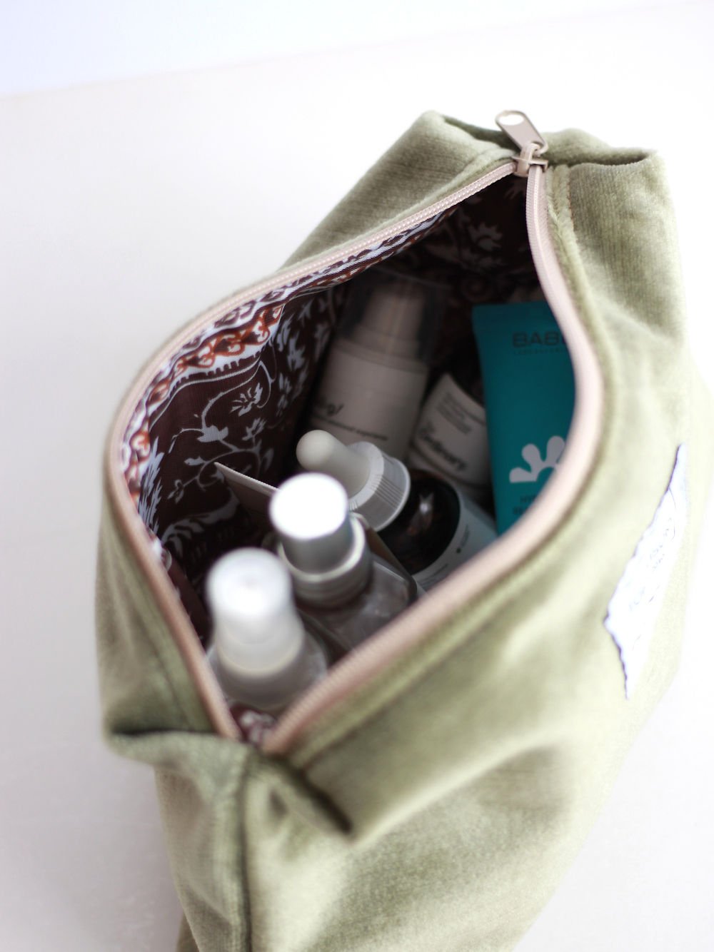 3. Interior view of LORNA Makeup Bag in olive velvet, showcasing spacious compartment with beauty products