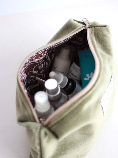 3. Interior view of LORNA Makeup Bag in olive velvet, showcasing spacious compartment with beauty products