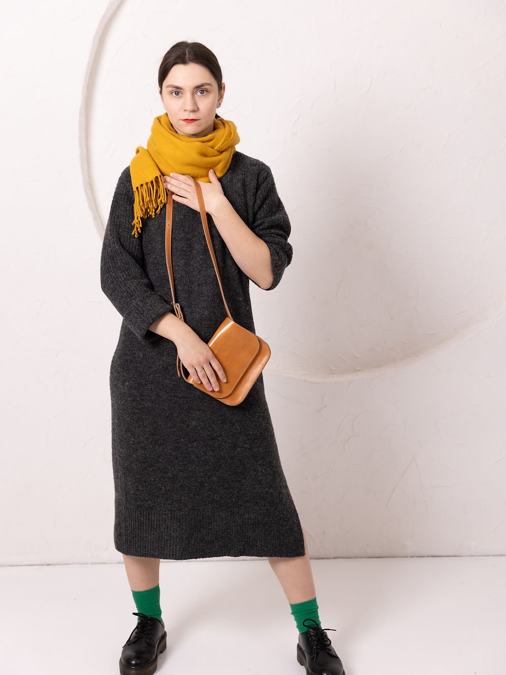 6. Woman wearing TOKS VISOKS RUBY Purse in caramel leather, styled with yellow scarf and dark dress