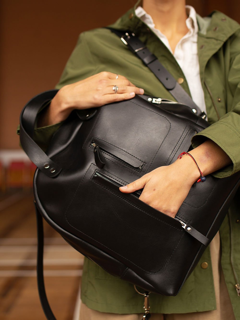 5. Close-up of TOKS VISOKS GORDON black leather backpack, highlighting front zipped pockets and recycled leather material