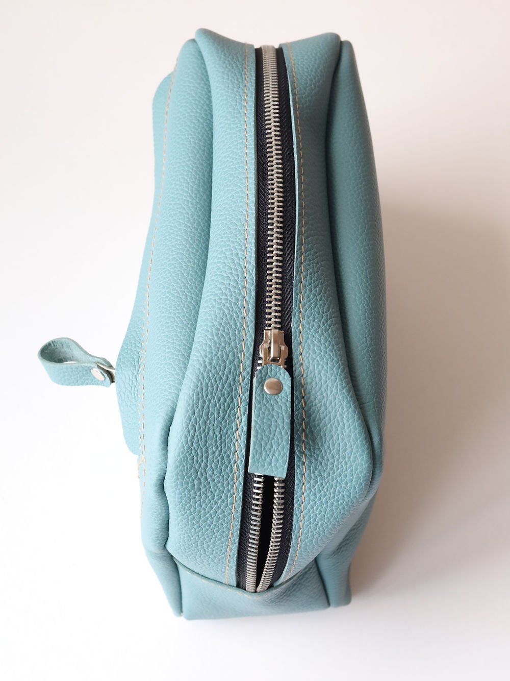 4. Side view of TOKS VISOKS DOUGLAS turquoise toiletry bag, showing durable zipper and compact design