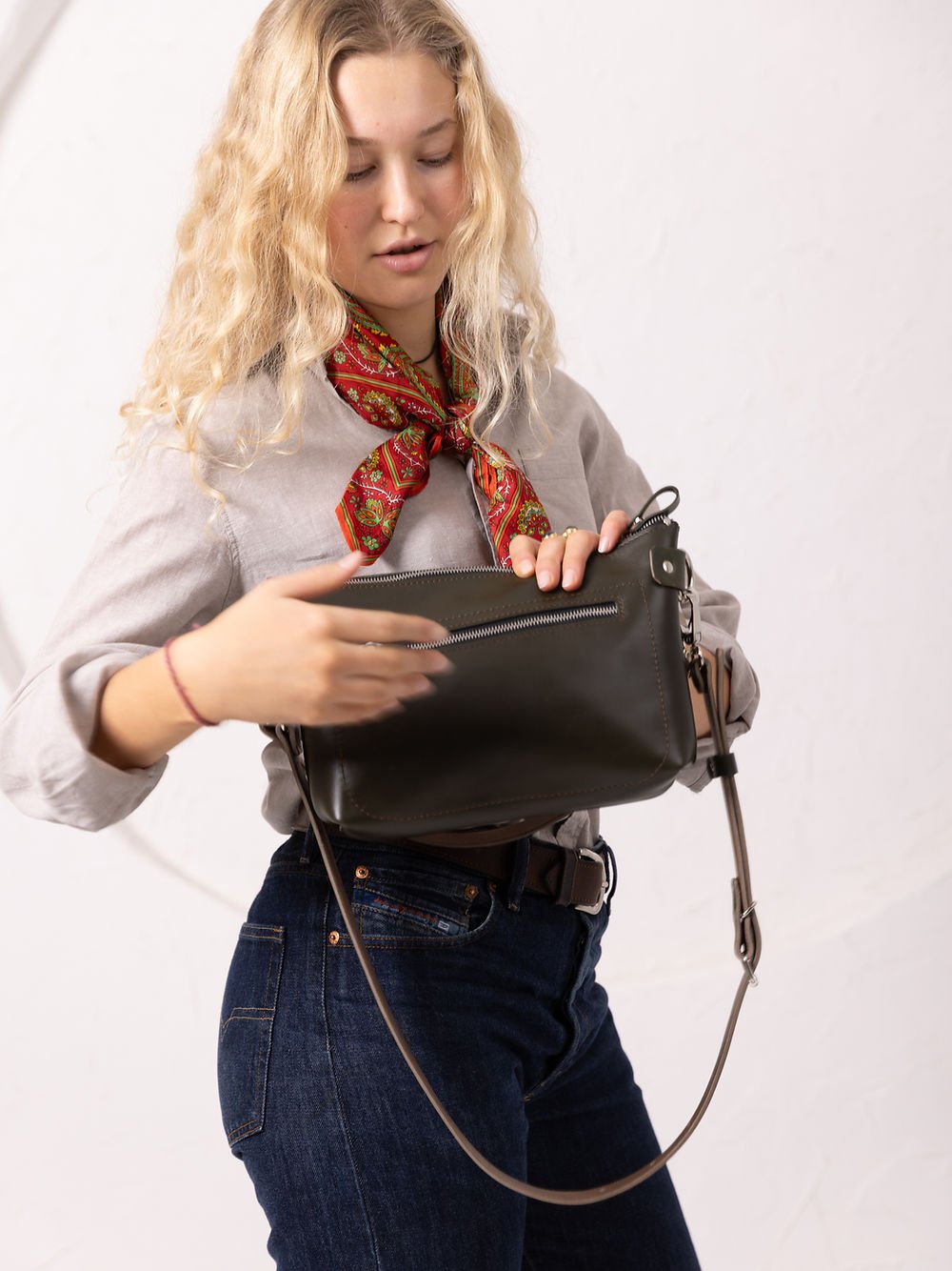 2. Close-up of women's TOMMY leather bag in dirty green, highlighting zipper closure and adjustable strap