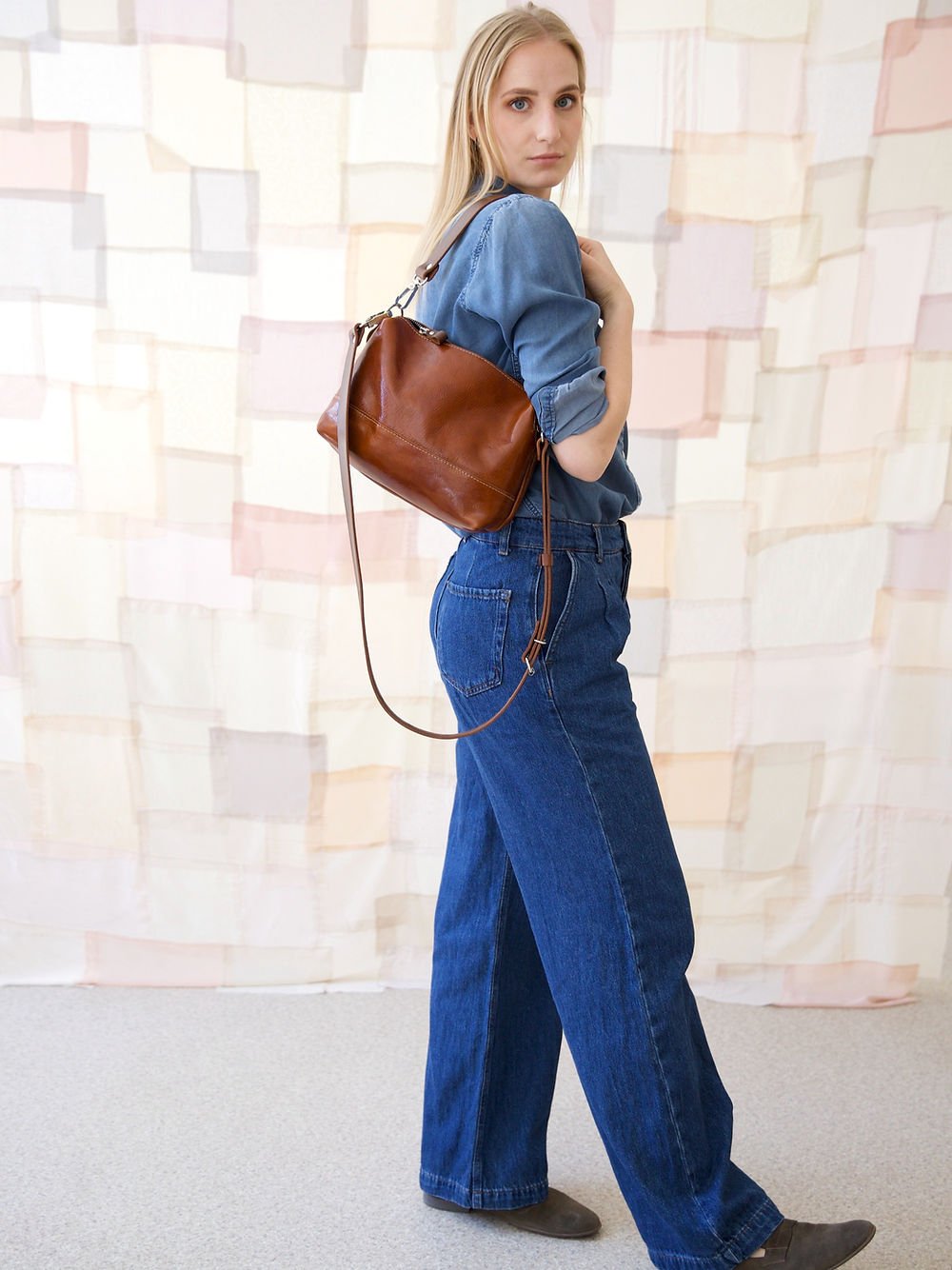 5. Woman posing with TOKS VISOKS ROBIN leather handbag in ginger brown, shown from back