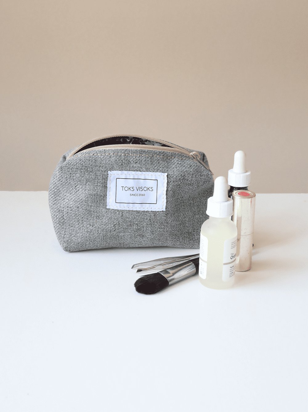 3. TOKS VISOKS LORNA grey makeup bag styled with beauty products in studio setting