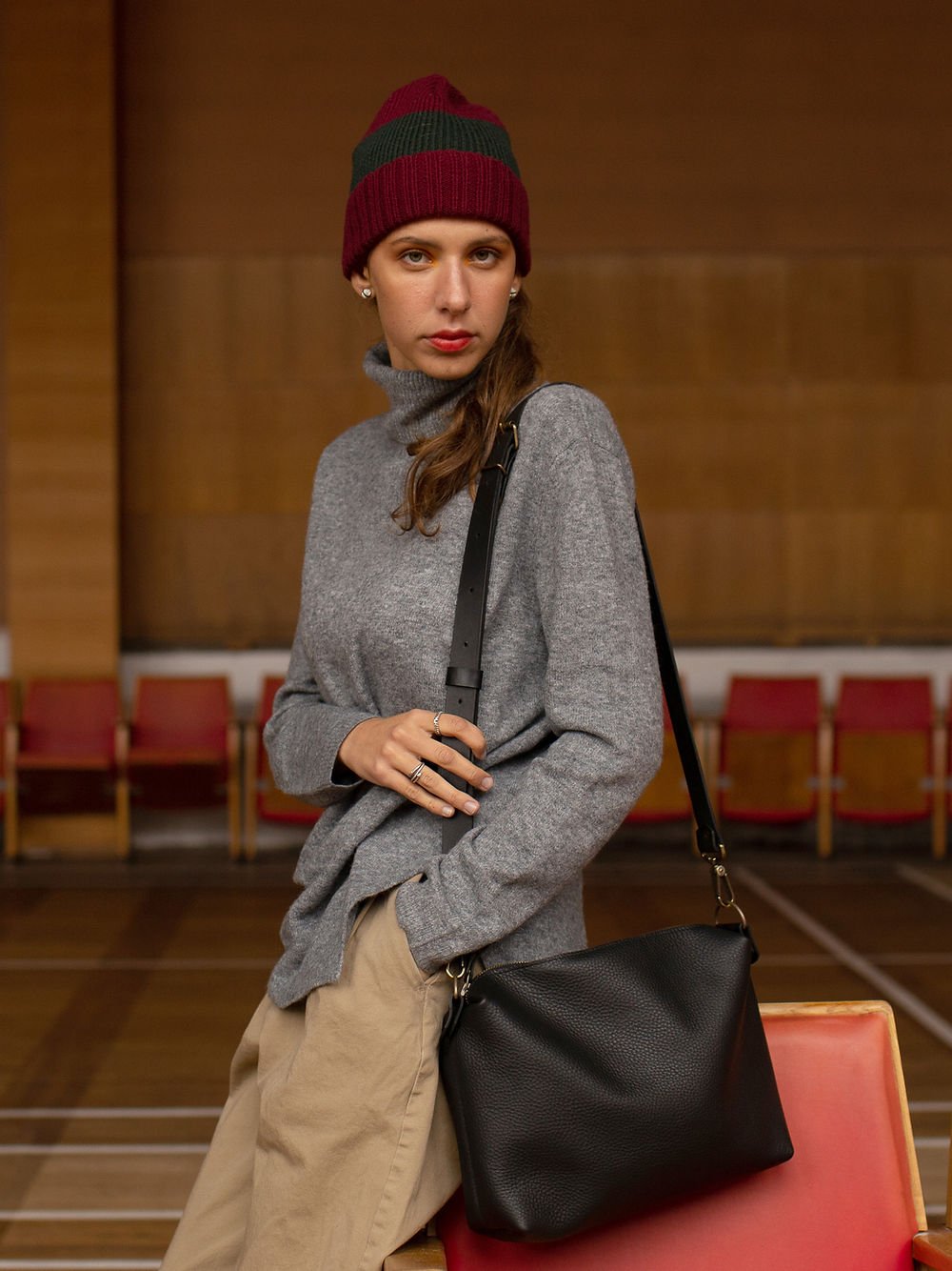 2. Woman holding TOKS VISOKS ROBIN large black leather handbag, showcasing adjustable strap and elegant design in lifestyle setting