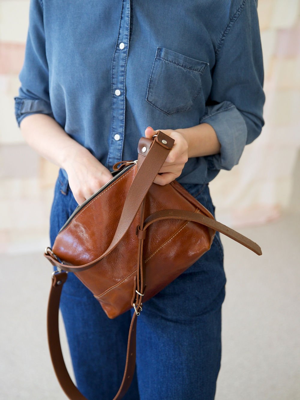 8. Close-up of TOKS VISOKS ROBIN leather handbag in ginger brown, showing zipper closure and handle
